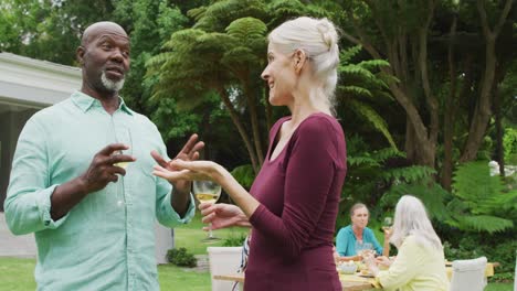 animation of diverse happy senior female and male friends talking in garden