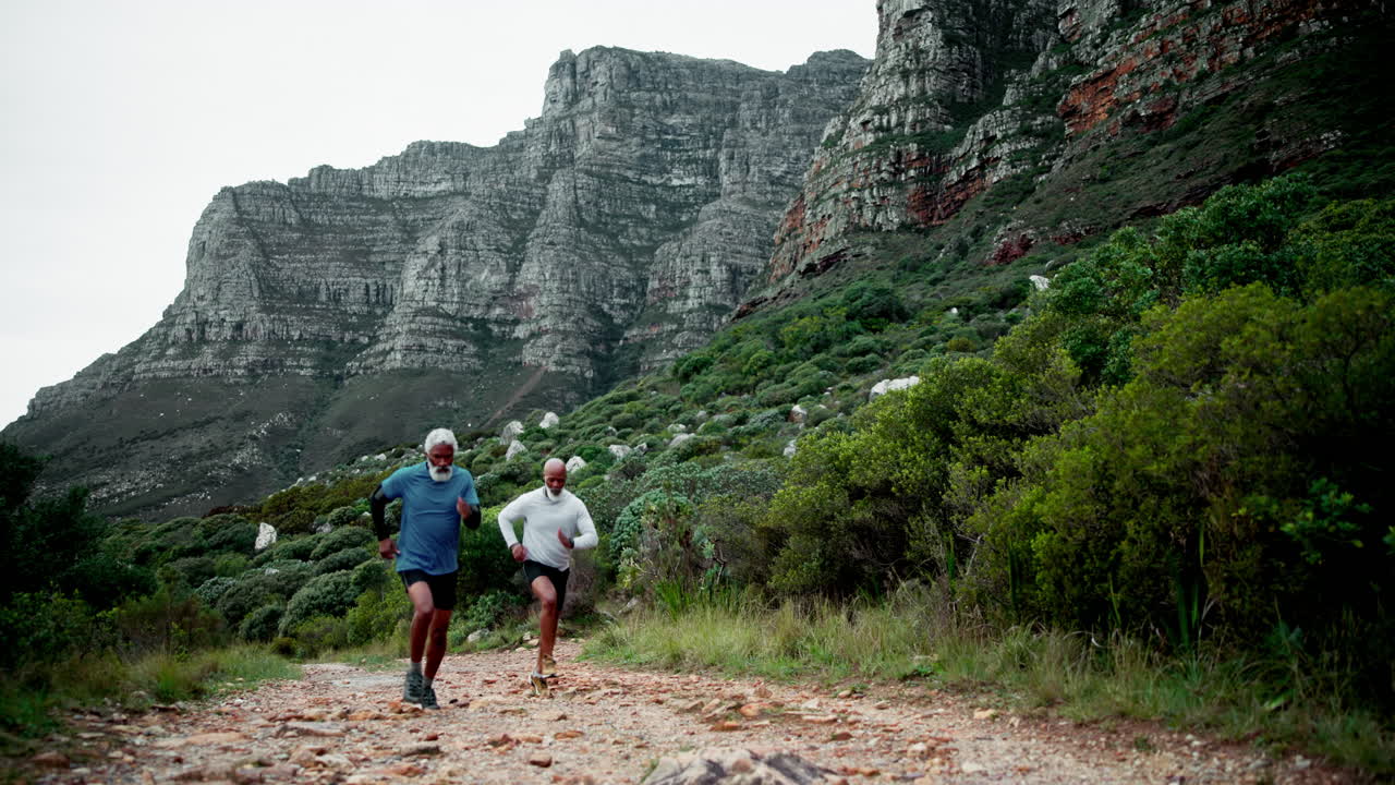 Two senior men running a mountain trail