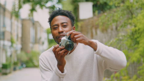 young man in city taking photo on digital camera to post to social media