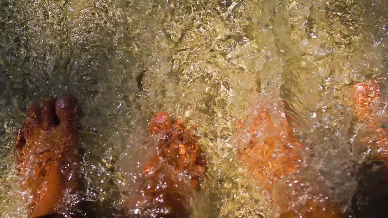 개울에 서있는 두 사람과 맑은 물이 발을 통해 흐르고 있습니다.