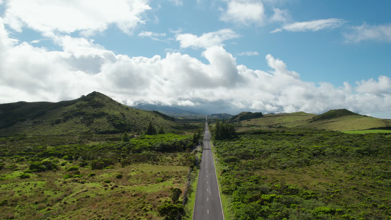 Voo para frente sobre uma estrada que atravessa o campo