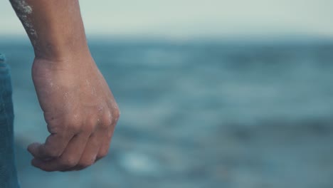 man's hand by his side standing in front of seaside