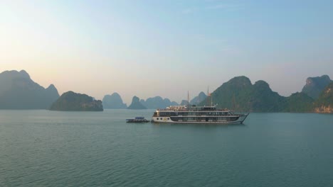 ha long bay twilight: cruise boats passing by rocky limestone mountains in the evening light