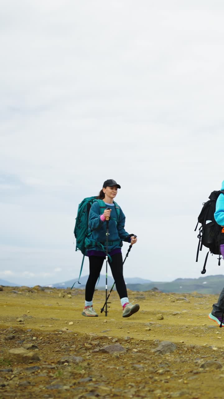 Due donne in escursione con zaini e bastoncini da trekking su un sentiero di montagna roccioso