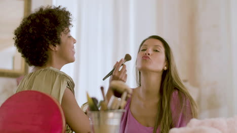 young black woman doing make-up on her female friend