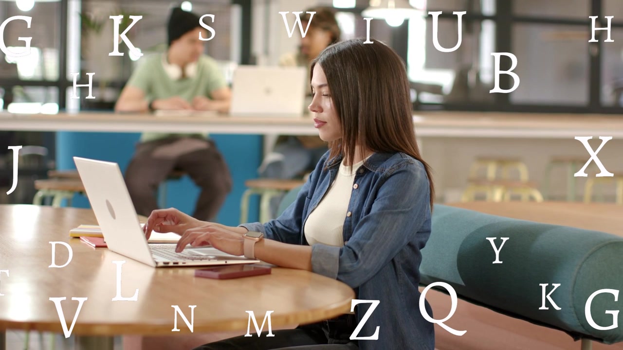 Video verticale: Donna che digita sul laptop a un tavolo, creando lettere che fluttuano sul soggetto per un progetto di design.