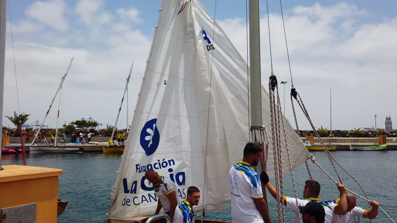 small lateen sail boat where its sailors prepare the sails to set sail from the port on a sunny day in Las Palmas de Gran Canaria. Spain.