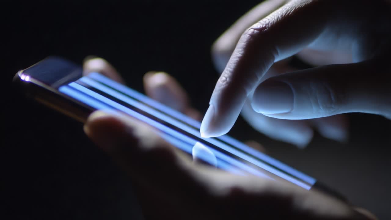 A close-up view of a person's hand interacting with a smartphone screen, showcasing the intricate details of touch gestures and the vibrant glow of the display amidst a dark background