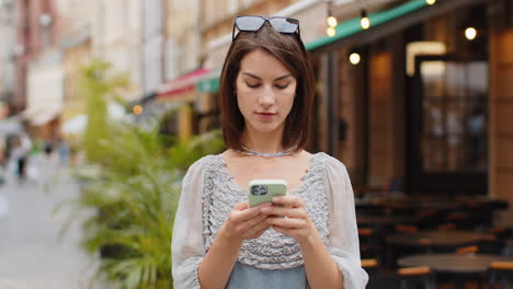 young woman use smartphone typing text messages browsing internet finishing work looking at camera