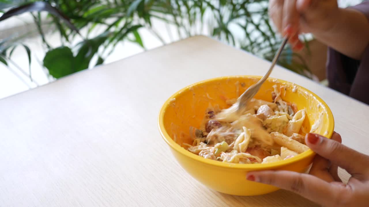 persona que come ensalada de pasta