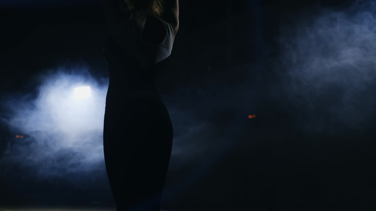 joven gimnasta corre y realiza volteretas hacia adelante y atornilla en el aire en cámara lenta en el gimnasio en la alfombra