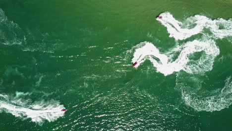 bird's eye view of jet skis almost crashing in yellow and green water