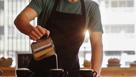 camarero sonriente haciendo una taza de café en el mostrador