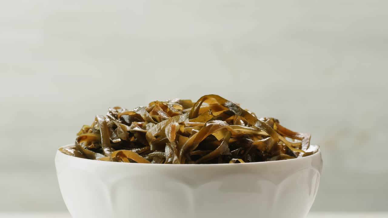 Japanese wakame sea weed laminaria chuka fermented food. Close-up on a detail of Hiyashi Wakame Chuka or seaweed salad or seaweed with sesame seeds on a plate. Top view. Seafood background.