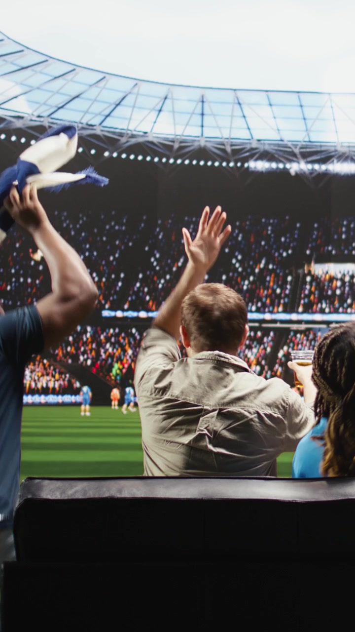 Video vertical: Aficionados al fútbol viendo un partido en un televisor con tecnología inmersiva, molestos por un gol