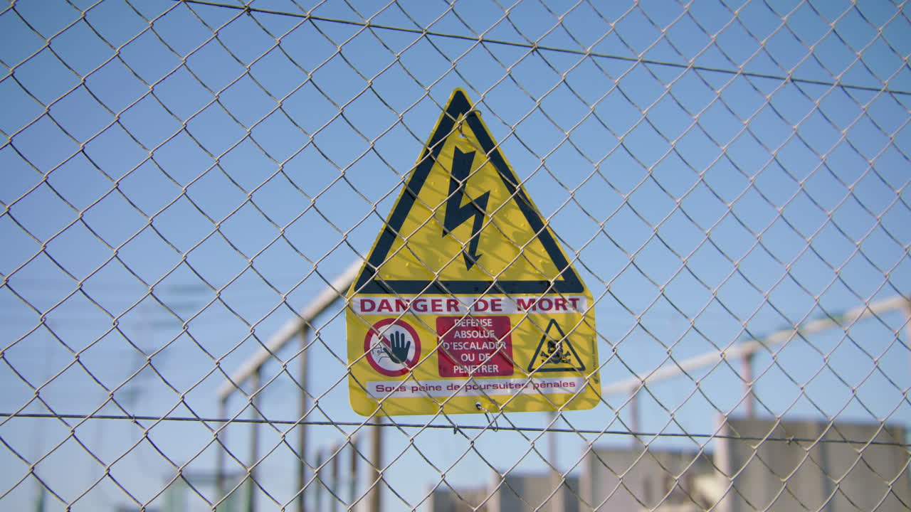 노란색 전기 충격 위험 신호가 높은 울타리에 표시되어 있습니다.