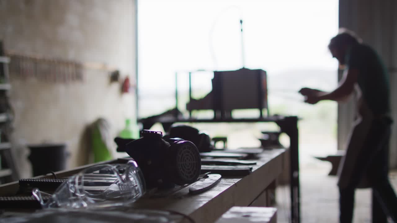 Caucasian male blacksmith holding hot metal tool in kiln with tongs in workshop