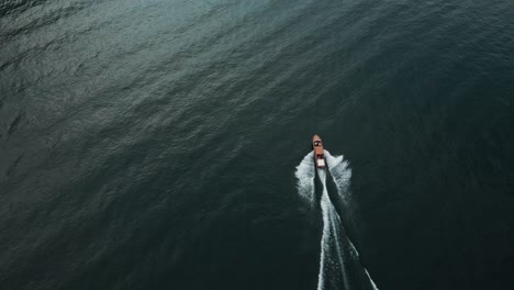 un disparo de un dron rastreando un barco mientras se desliza a través de las aguas oscurecidas del lago como