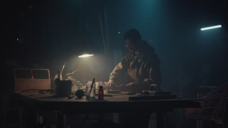 a bombmaker assembles a bomb in his workshop at night
