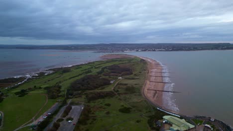 early morning aerial drone flight over dawlish warren spit with exmouth, devon in the distance showing narrow entrance to the river exe and the exe estuary near exeter