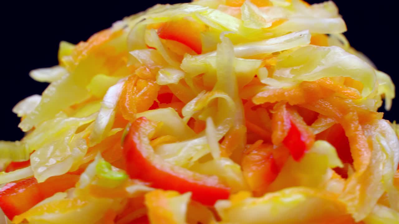 색 접시 위에 신선한 채소 러드가 검은색 배경에 회전합니다.