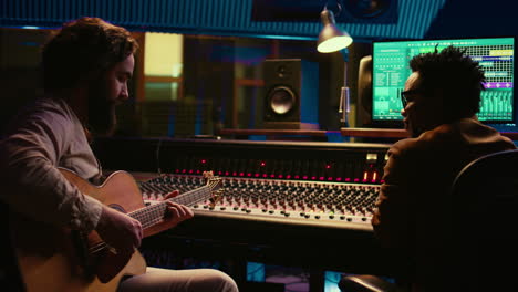 musician and sound engineer recording guitar tunes in control room