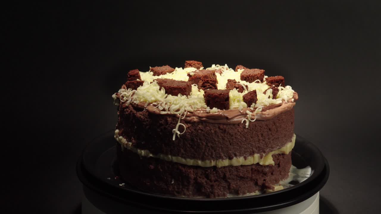 Brownie e cheesecake, deliziosa prelibatezza dolce e gustosa su un piatto girevole con sfondo nero
