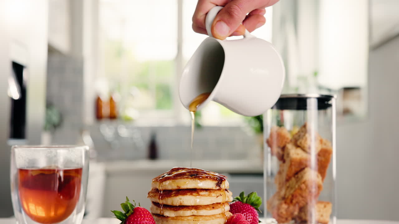 Versare sciroppo su una pila di pancake con frutti di bosco freschi