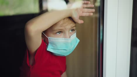 young boy in a medical mask looks out the window 02