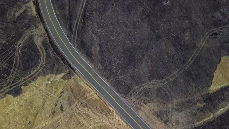 Drone-panning-up-from-road-cutting-across-fire-damaged-field-to-reveal-fire-damage-in-Northern-California-Lassen-County