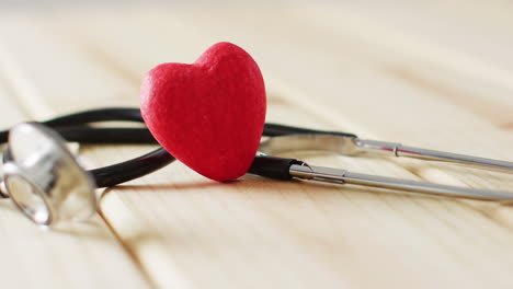video de estetoscopio con corazón rojo en fondo de madera con espacio de copia