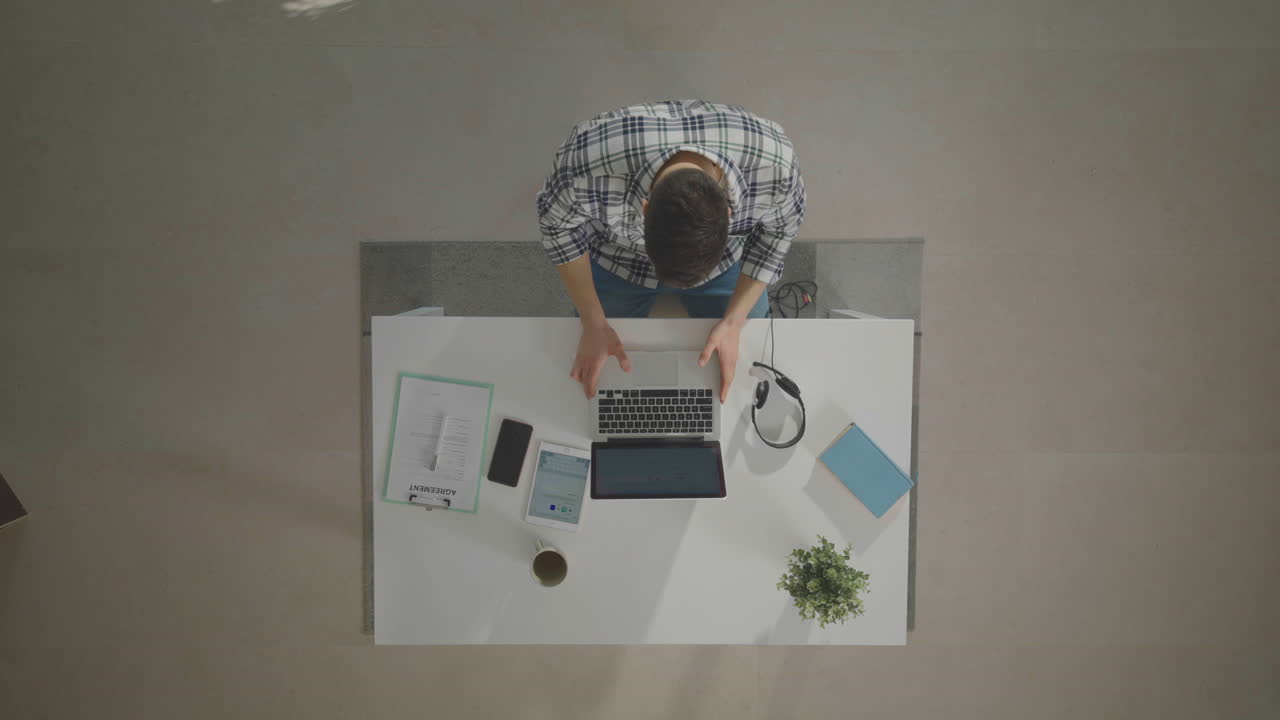 Man sitting at desk and opening laptop