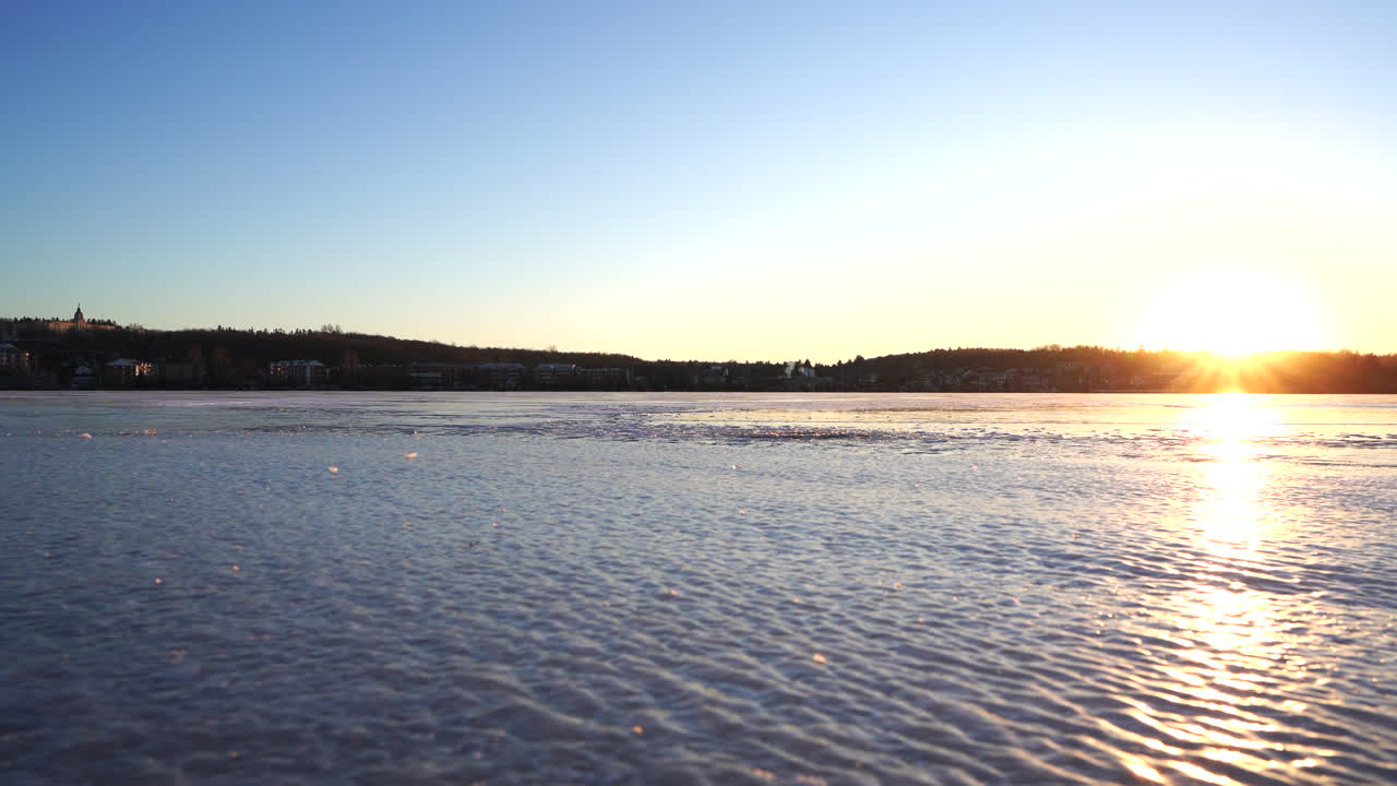 일몰에 의해 겨울에 얼어붙은 호수의 팬 샷