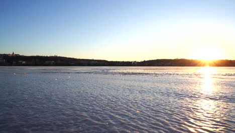 Pan-shot-of-a-frozen-lake-in-winter-by-sunset