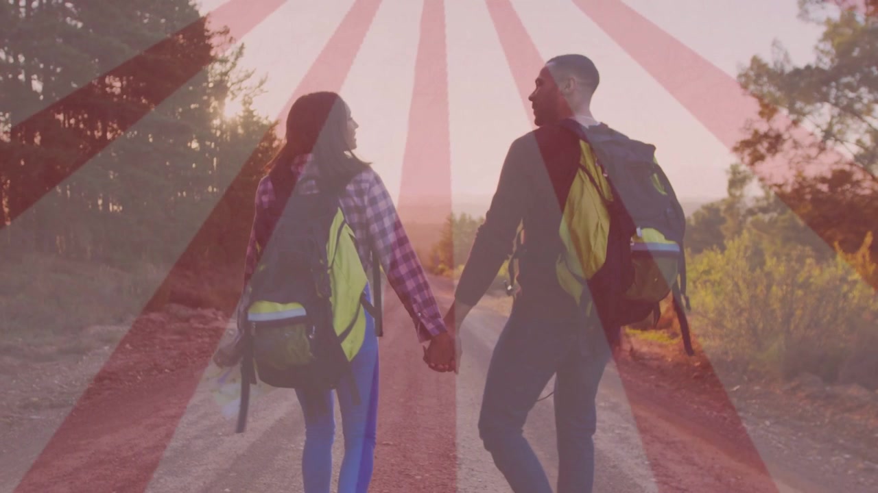 Pair walking down dirt rd to dusk holding map, packs, travel sunburst overlay appearing on horizon