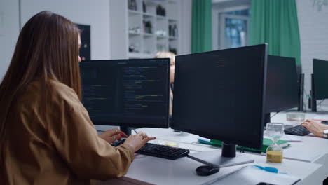 A woman working on code in an office with a team of people