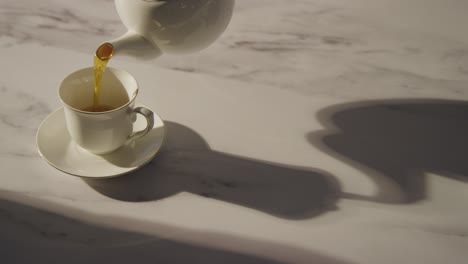 studio shot of person making and pouring traditional british cup of tea using teapot 2