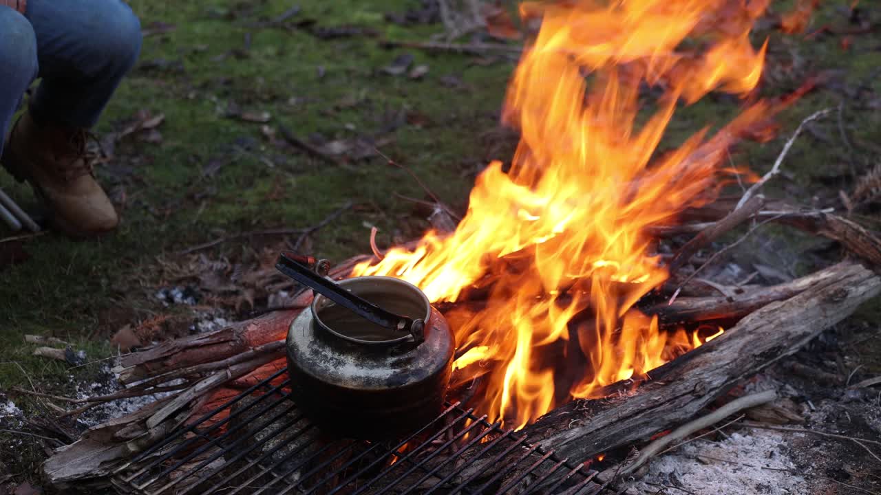 una olla de agua hirviendo sobre un fuego en el monte en el país alto australiano