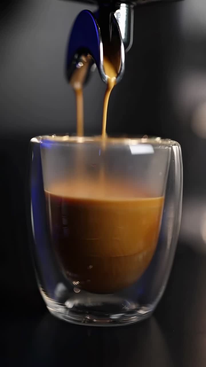 Video ravvicinato di caffè espresso che si versa in una tazza di vetro, che cattura texture ricche e colori