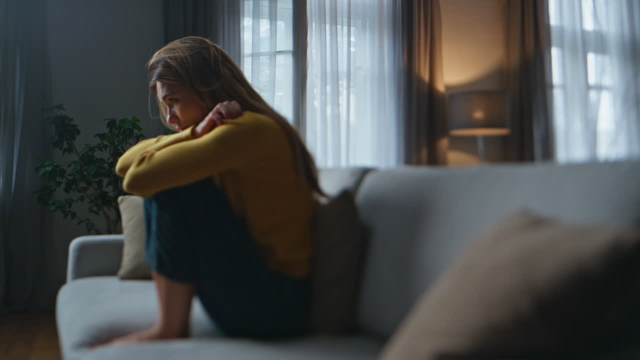 Ragazza turbata che si sente male seduta sul divano di notte a casa. Donna triste che soffre per una rottura.