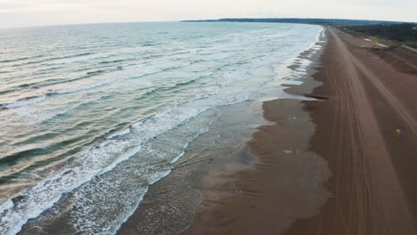 Car-Driving-on-Beach,-Aerial-Reveal-of-Ocean-and-Seaside-4k