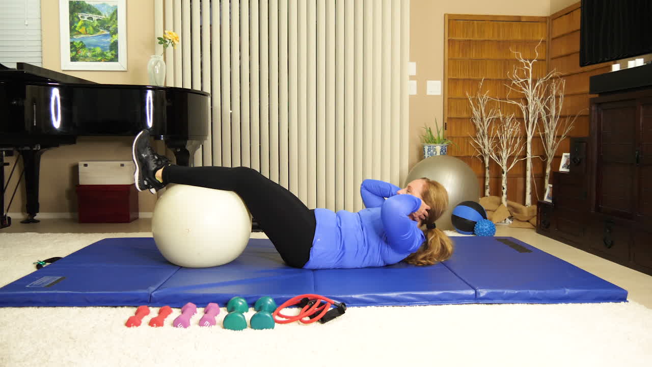mujer adulta haciendo ejercicio en casa haciendo abdominales con pelota de estabilidad debajo de las rodillas, retrato, tiempo real