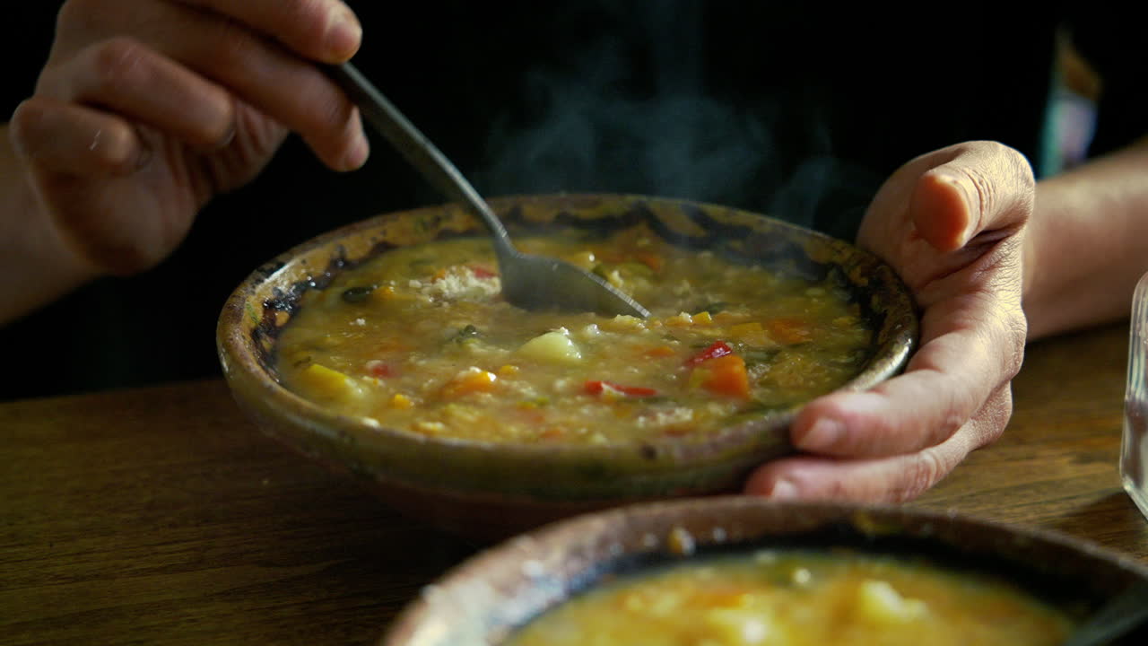 Close-up de Mãos Mexendo Sopa de Vegetais Quente com Queijo Ralado