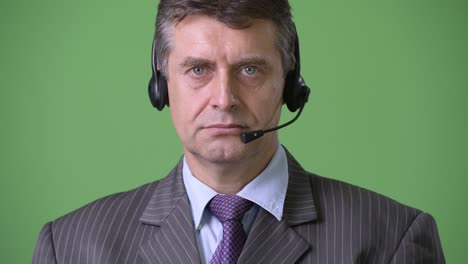 mature handsome businessman against green background