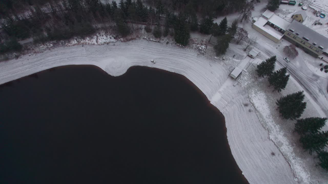 Bottom-up view of a drone on snowy wooded nature in winter, with a foggy horizon and mountains. Vír, Czech Republic