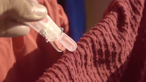 una clavija de plástico blanca pegada a una camisa roja colgada en una cuerda de ropa