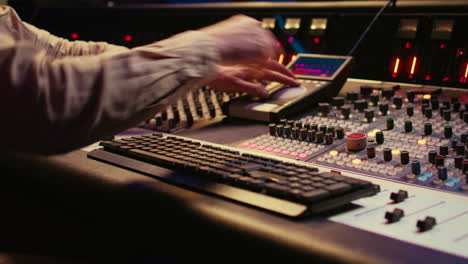 audio technician uses mixing console and faders in control room