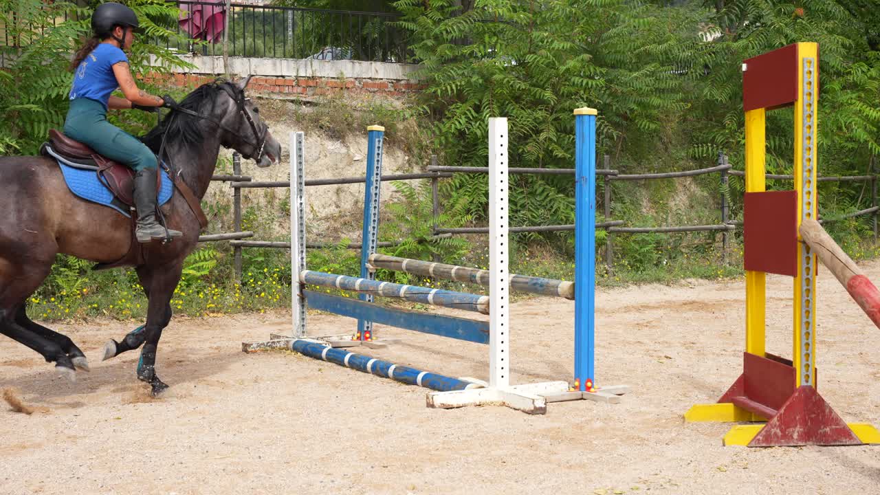 Bagfra-perspektiv af en rytter, der springer over et forhindring under et ridebanespringningsstævne. Slowmotion.