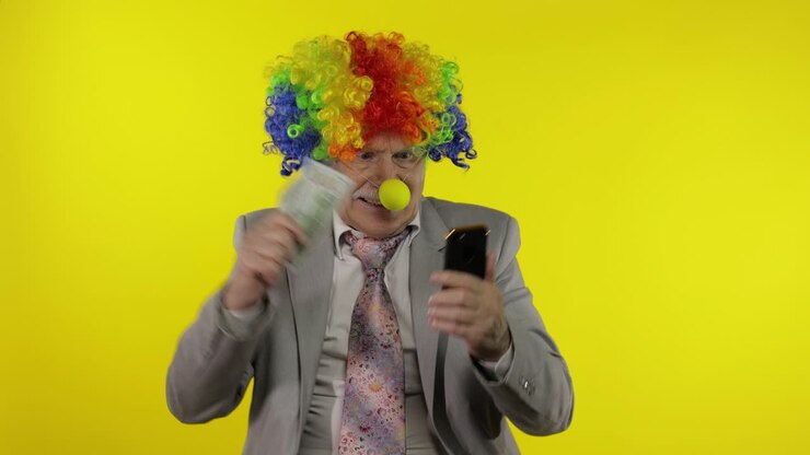 Senior clown businessman entrepreneur loses money while working on phone online