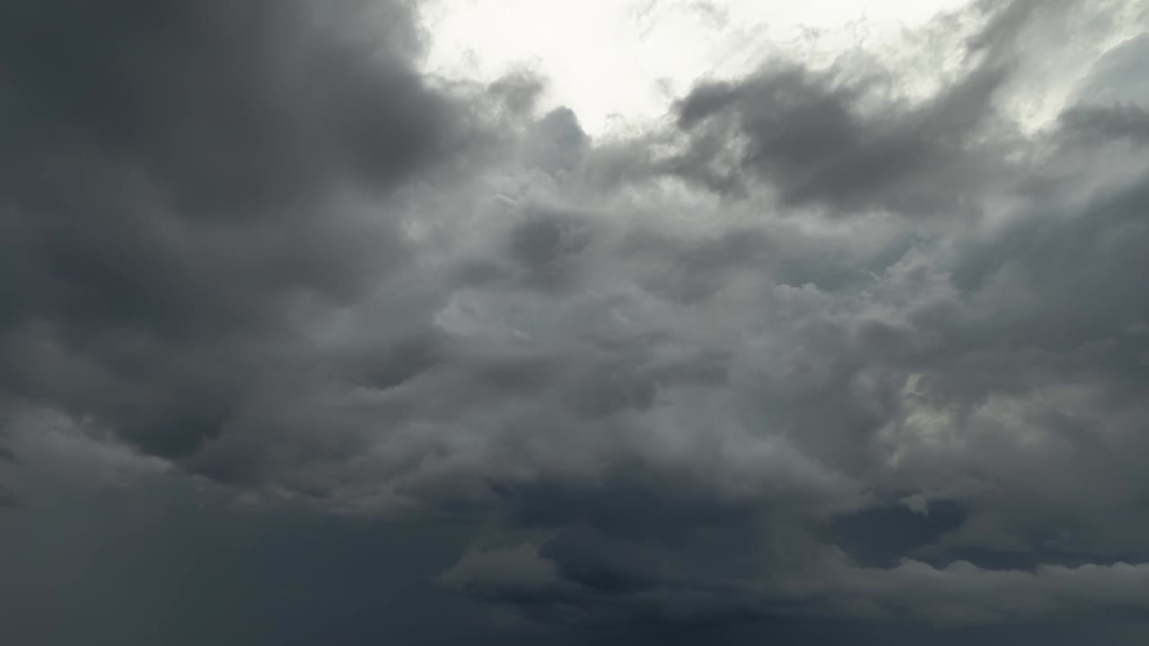 털 모양의 회색 폭풍 구름이 어지고 구름이 가득한 하늘에서 어지기 시작하며, 빛은 상층 구름을 다른 방향으로 움직입니다.